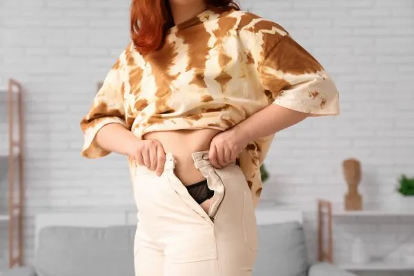 Image of woman trying to do her trousers up after pregnancy weight gain Amersham